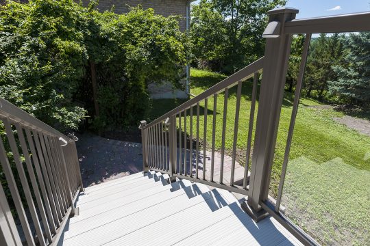 Light grey composite deck boards and stairs in a sunny backyard