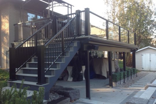 Black aluminum railing on a dark composite deck with stairs at dusk