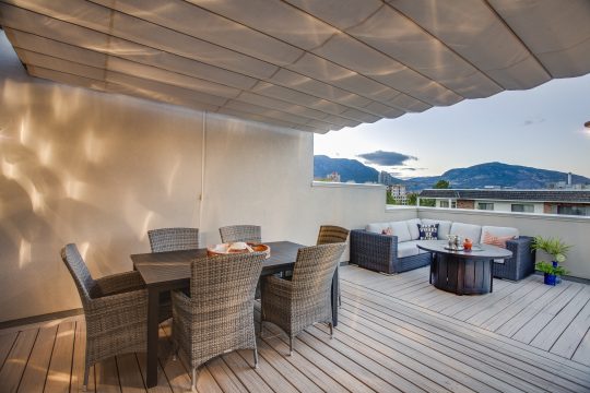 Solid cream retractable canopy shading a rooftop terrace with dining and lounge seating