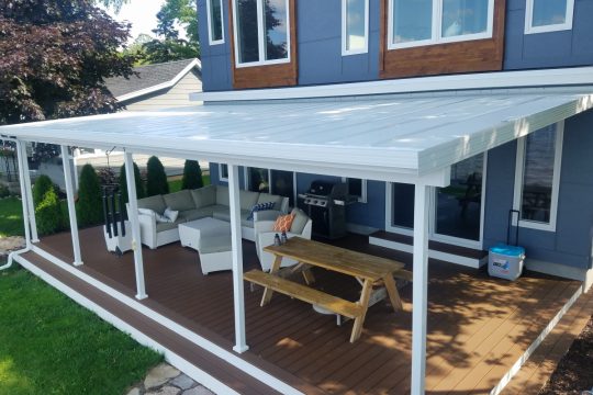 PanelCraft insulated white aluminum roof shading a composite deck beside a blue home